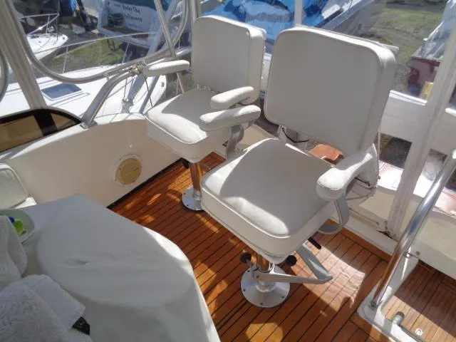 Slide: The Image of 1999 Albemarle 325 Convertible boat interior with two white captain's chairs on wooden deck. - 20