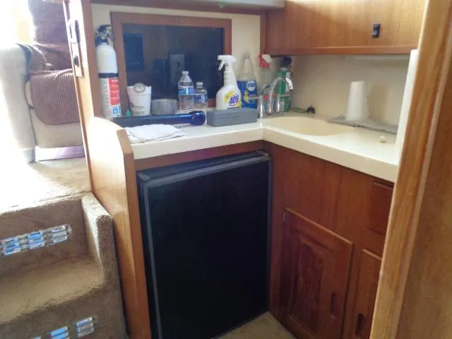 Slide: The Image of 1999 Albemarle 325 Convertible boat kitchen with sink, cleaning supplies, and mini fridge. - 40