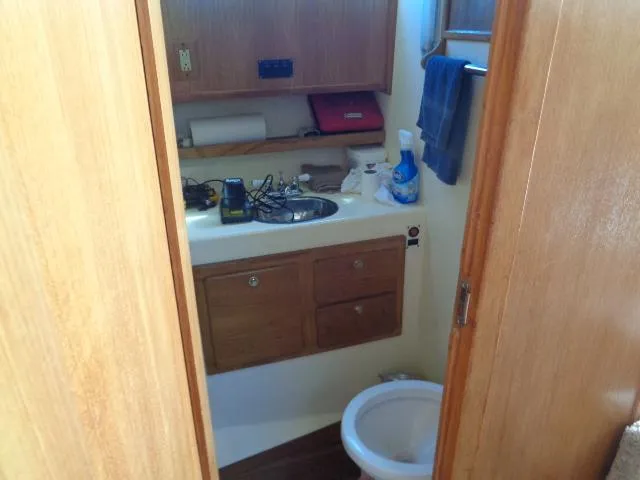 Slide: The Image of 1999 Albemarle 325 Convertible boat bathroom with sink, toilet, and wooden cabinets. - 42