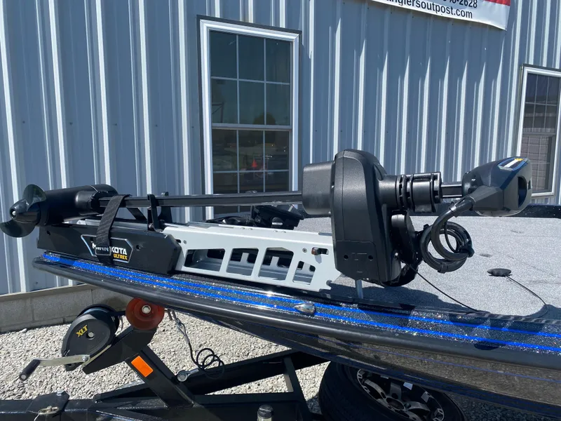 Slide: The Image of 2025 Phoenix 721 ZXL boat with Minn Kota trolling motor, parked outside a metal building. - 4