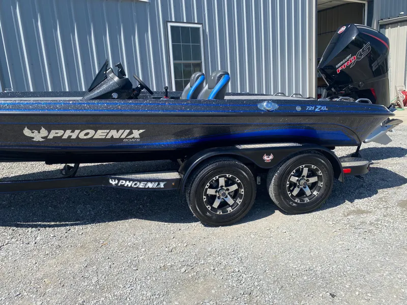 Slide: The Image of 2025 Phoenix 721 ZXL boat with dual axle trailer parked outside a metal building. - 6