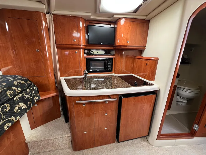 Slide: The Image of 2006 Four Winns 348 Vista yacht interior with kitchenette, wood cabinets, and compact appliances. - 3