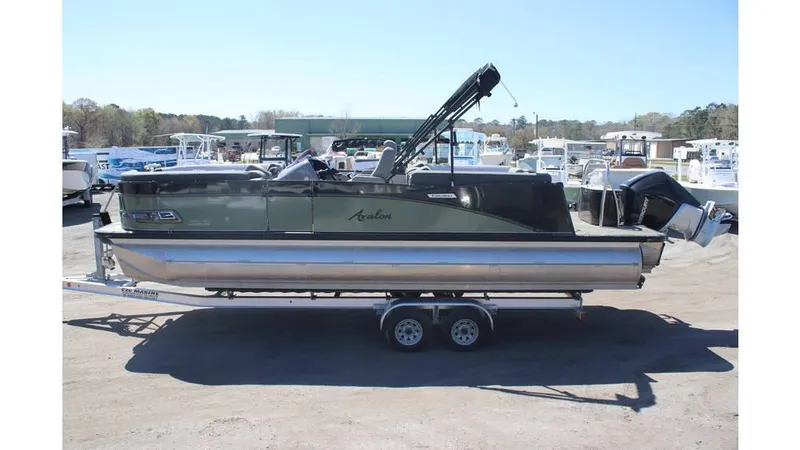Slide: The Image of 2022 Avalon Catalina Quad Lounger pontoon boat on trailer, parked in marina. - 2