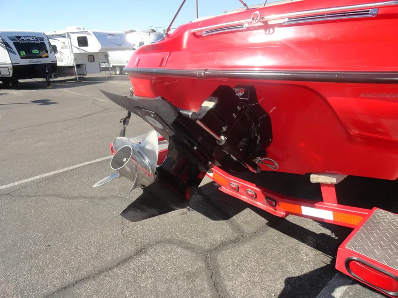 Slide: The Image of Red 2001 Crownline 202 BR LPX boat with visible propeller and trailer in parking lot. - 22