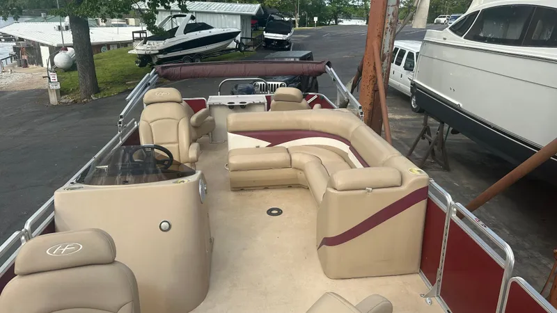 Slide: The Image of 2014 Harris Cruiser 240 pontoon boat with beige seating and maroon accents, docked outdoors. - 5