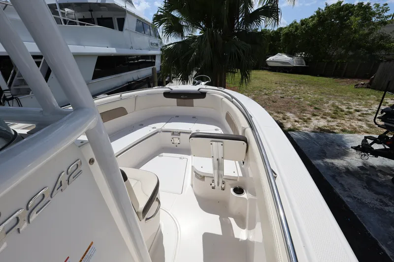 Slide: The Image of 2019 Robalo R242 Explorer boat interior with seating and storage, docked near palm trees. - 15