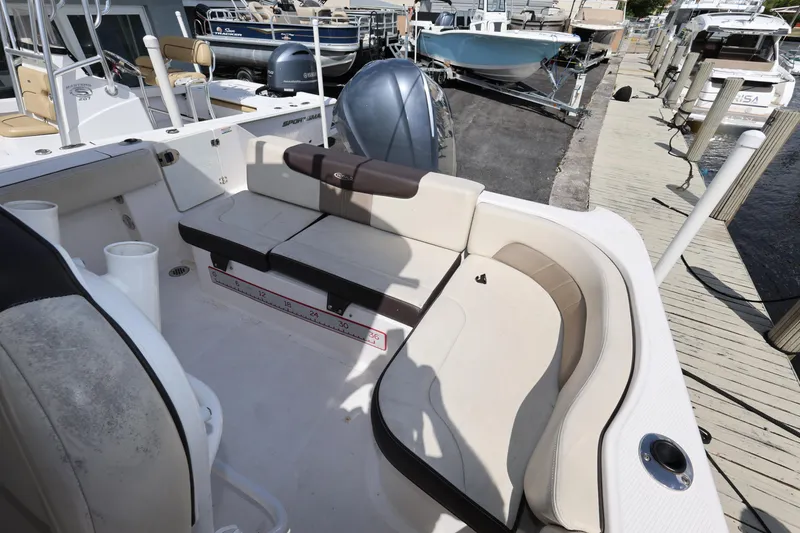 Slide: The Image of 2019 Robalo R242 Explorer boat interior with cushioned seating and docked boats in background. - 23