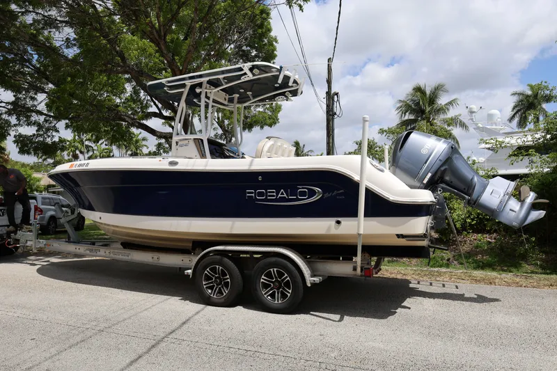 Slide: The Image of 2019 Robalo R242 Explorer boat on trailer, parked on street under trees. - 3