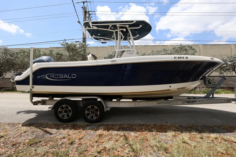 Slide: The Image of 2019 Robalo R242 Explorer boat on trailer, parked outdoors under blue sky. - 6
