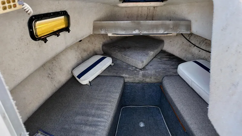Slide: The Image of 1998 Bayliner Trophy 1802 Cuddy cabin interior with cushioned seating and small window. - 12