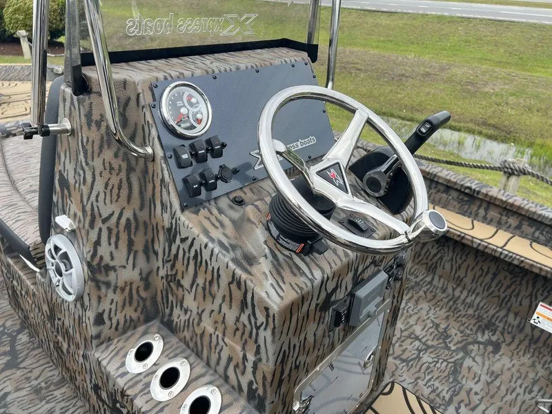 Slide: The Image of 2025 Xpress X23B Lounge boat dashboard with camo design and steering wheel. - 10