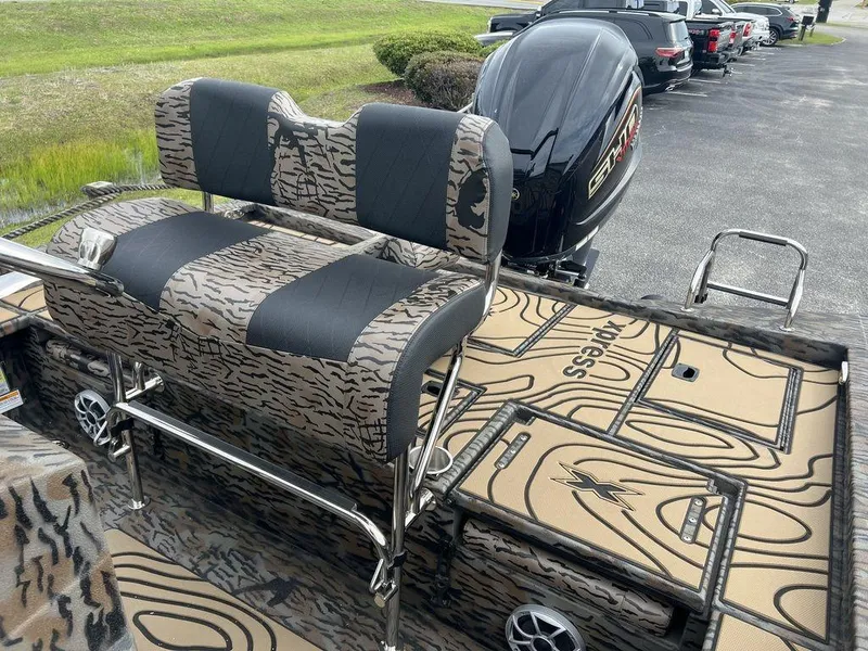 Slide: The Image of 2025 Xpress X23B Lounge boat with camo seating and powerful outboard motor. - 11