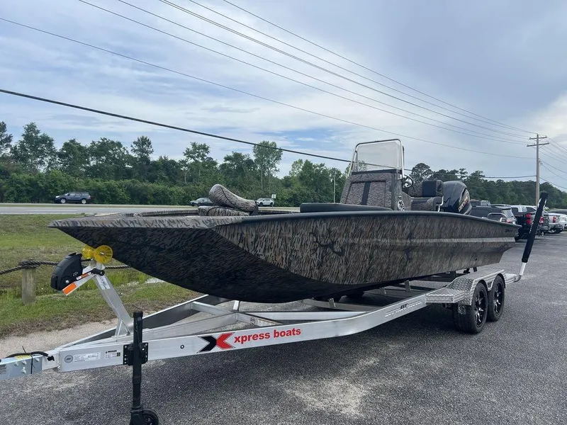 Slide: The Image of 2025 Xpress X23B Lounge boat on trailer, parked outdoors, showcasing sleek design and camouflage pattern. - 3