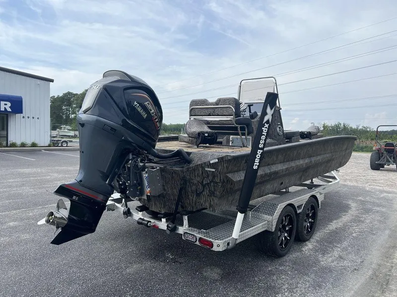 Slide: The Image of 2025 Xpress X23B Lounge boat on trailer, featuring powerful outboard motor. - 6