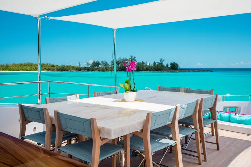 Slide: The Image of Luxury yacht deck with dining table, ocean view, and vibrant orchid centerpiece. Mengi Yay 105 Explorer. - 24