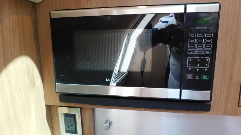 Slide: The Image of Microwave inside 2017 Boston Whaler 315 Conquest boat cabin, featuring wood paneling. - 11