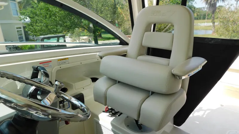 Slide: The Image of Captain's chair in 2017 Boston Whaler 315 Conquest boat cockpit, featuring steering wheel and controls. - 22