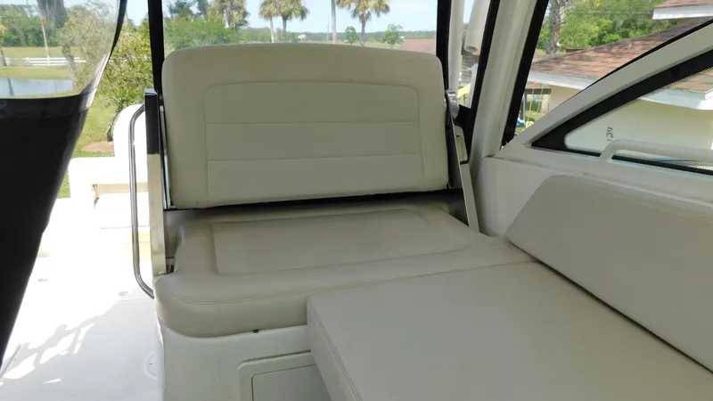Slide: The Image of 2017 Boston Whaler 315 Conquest interior seating with beige upholstery and outdoor view. - 24
