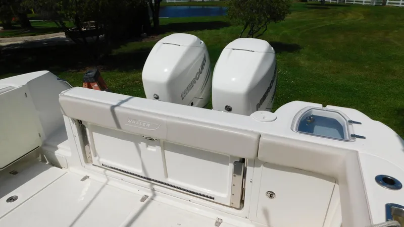 Slide: The Image of 2017 Boston Whaler 315 Conquest boat with dual outboard engines, docked on grassy area. - 32