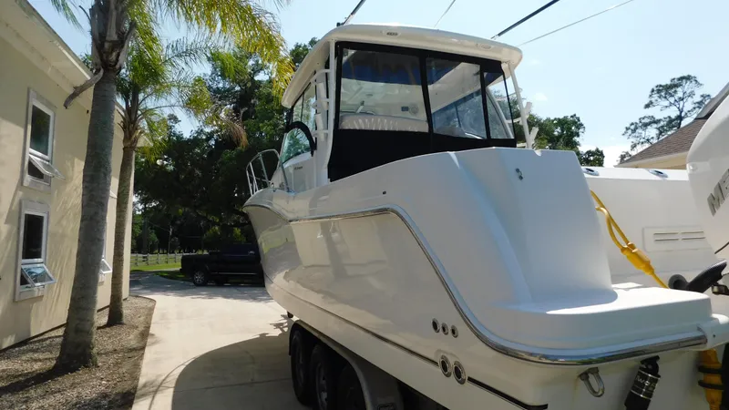 Slide: The Image of 2017 Boston Whaler 315 Conquest boat parked outdoors, surrounded by trees and buildings. - 48