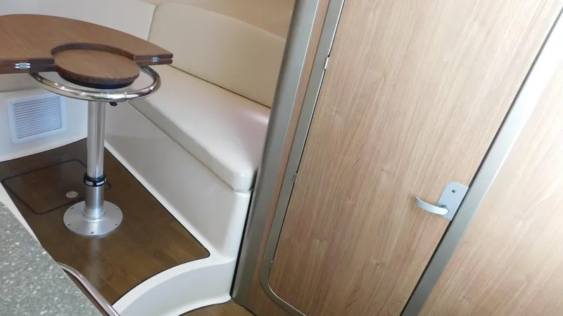 Slide: The Image of 2017 Boston Whaler 315 Conquest cabin interior with seating and wooden table. - 5