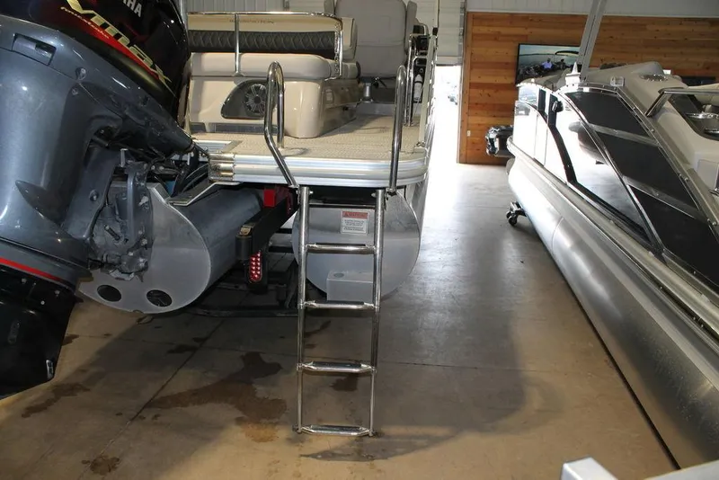 Slide: The Image of 2018 Bennington 25RSB pontoon boat with ladder and outboard motor in a showroom. - 13
