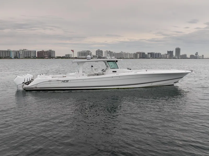 Slide: The Image of 2021 HCB Suenos boat on calm water with city skyline in background. - 11