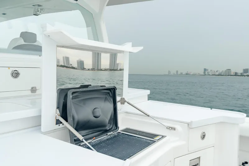Slide: The Image of 2021 HCB Suenos boat with open storage compartment, city skyline in background. - 23