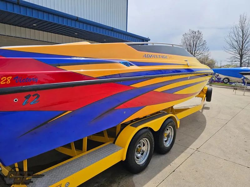 Slide: The Image of 2006 Advantage 28 Victory Bowrider with vibrant yellow, red, and blue design on trailer. - 10