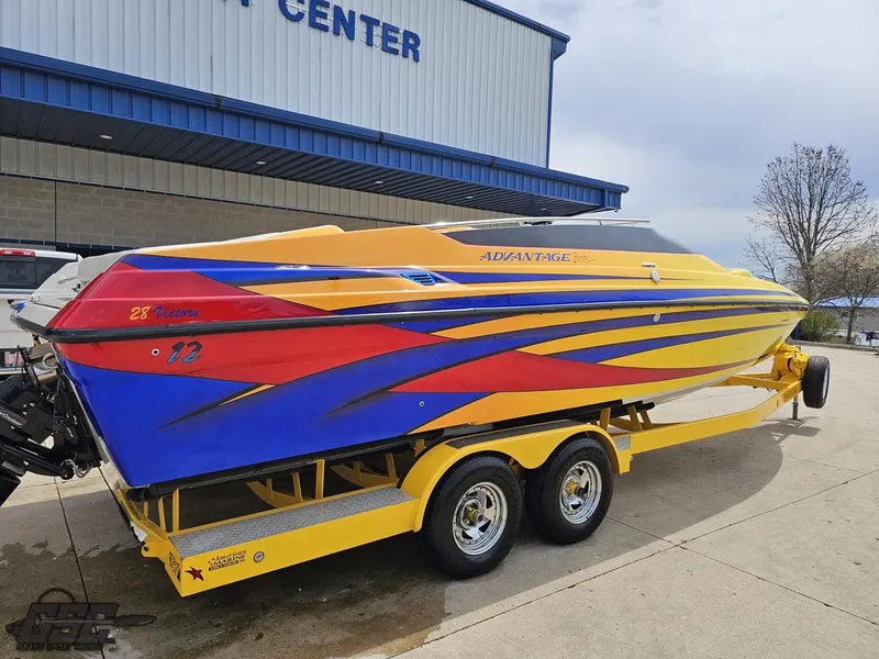 Slide: The Image of 2006 Advantage 28 Victory Bowrider boat with vibrant yellow, blue, and red design on trailer. - 33