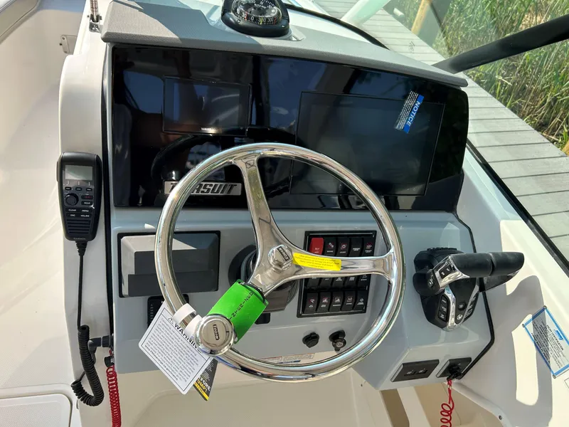 Slide: The Image of 2026 Pursuit DC 266 Dual Console helm with steering wheel, controls, and navigation equipment. - 13