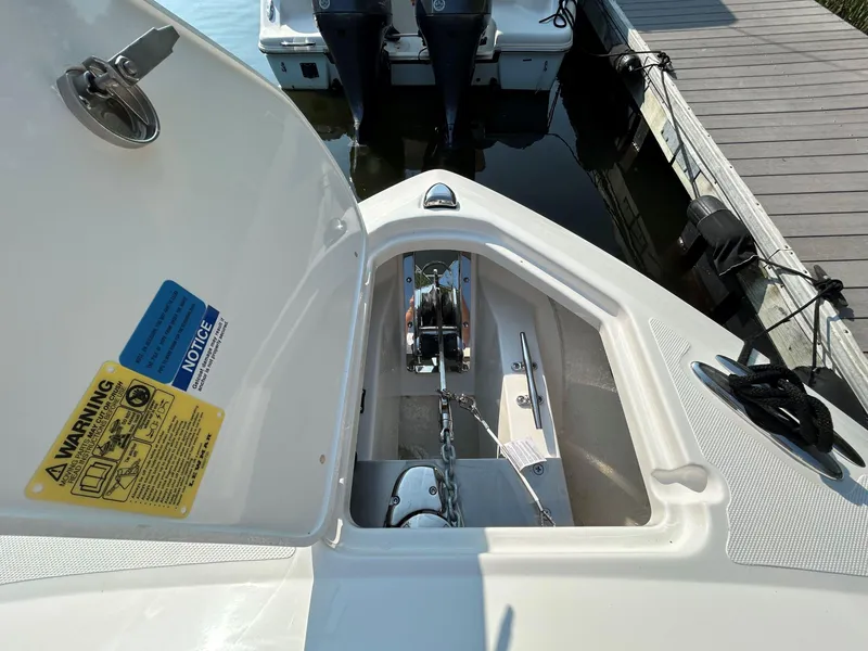 Slide: The Image of 2026 Pursuit DC 266 Dual Console anchor compartment with chain and warning labels. - 17