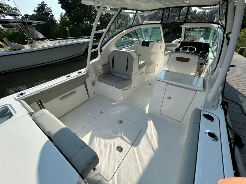 Slide: The Image of 2026 Pursuit DC 266 Dual Console boat interior with seating and helm, docked by the water. - 4