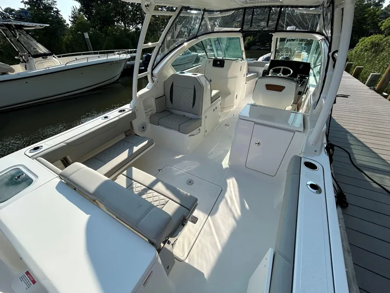 Slide: The Image of 2026 Pursuit DC 266 Dual Console boat interior with seating and helm, docked by the water. - 5