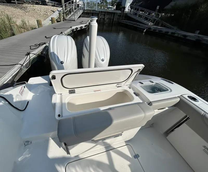 Slide: The Image of 2026 Pursuit DC 266 Dual Console boat with open storage compartment, docked by the water. - 6
