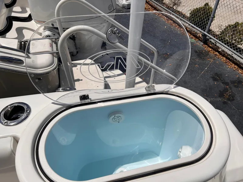 Slide: The Image of Open livewell on 2025 Key West 260 CC boat, featuring a clear lid and blue interior. - 28