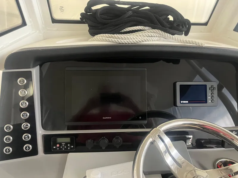 Slide: The Image of 2021 Robalo R272 Center Console dashboard with steering wheel, navigation screens, and coiled ropes. - 30
