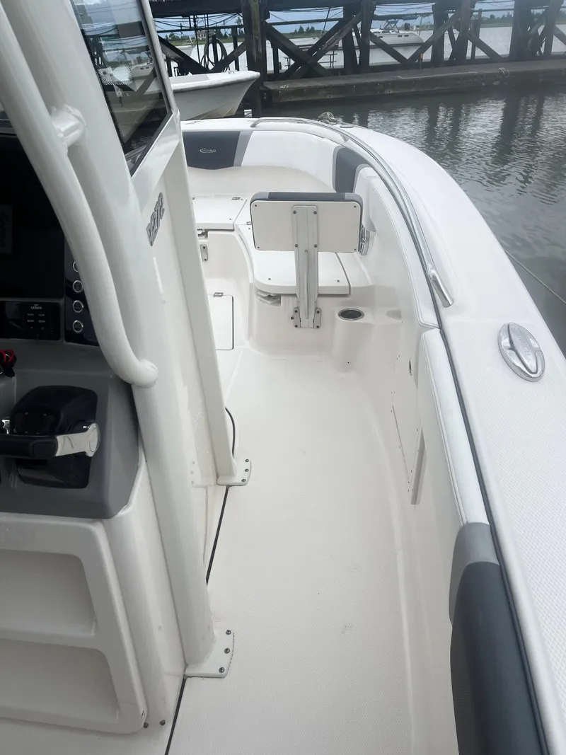Slide: The Image of 2021 Robalo R272 Center Console boat interior, featuring helm and seating, docked by the water. - 47