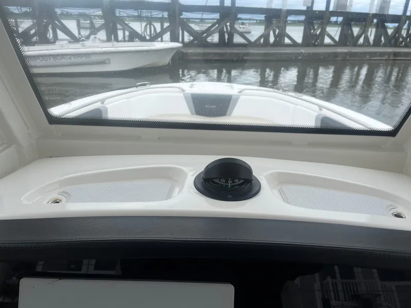 Slide: The Image of 2021 Robalo R272 Center Console boat dashboard with compass, docked at marina. - 49