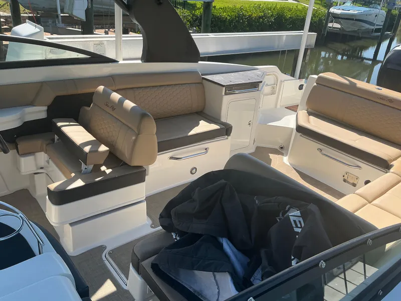 Slide: The Image of 2018 Sea Ray SDX 290 Outboard interior with beige seating and storage compartments. - 14