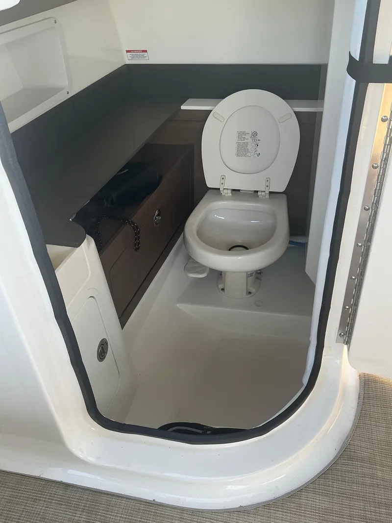Slide: The Image of 2018 Sea Ray SDX 290 Outboard boat bathroom interior with toilet and storage. - 18