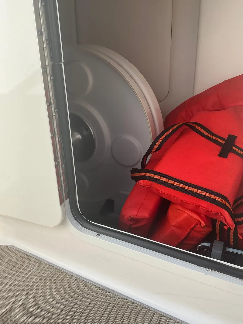 Slide: The Image of Storage compartment in a 2018 Sea Ray SDX 290 Outboard with life jackets and a spare wheel. - 28