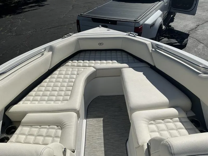 Slide: The Image of 2021 Cobalt R7 boat interior with white cushioned seating and a truck in the background. - 11