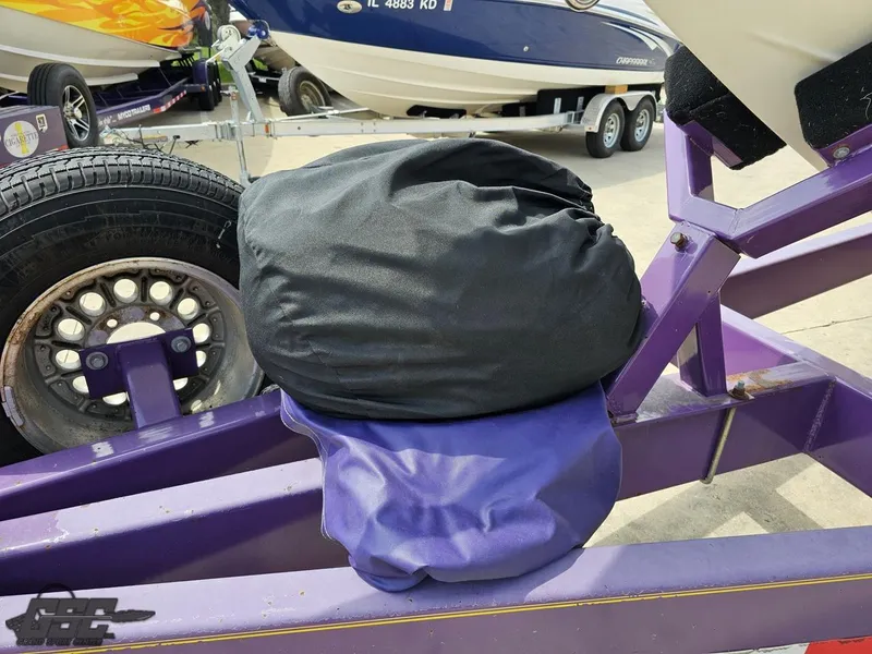 Slide: The Image of 1999 Powerquest 380 Avenger trailer with covered spare tire, purple frame, and nearby boats. - 15