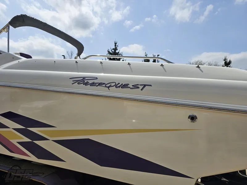 Slide: The Image of 1999 Powerquest 380 Avenger boat with sleek design and vibrant graphics under a blue sky. - 24