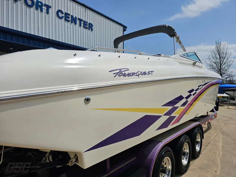 Slide: The Image of 1999 Powerquest 380 Avenger boat with vibrant graphics on a trailer at a port center. - 8