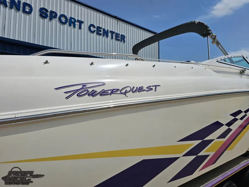 Slide: The Image of 1999 Powerquest 380 Avenger boat with colorful graphics, parked near a sports center. - 9