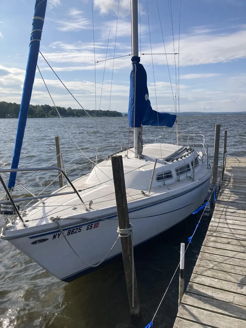 Slide: The Image of 1980 Catalina Cat 27 sailboat docked on a sunny day with blue skies. - 0
