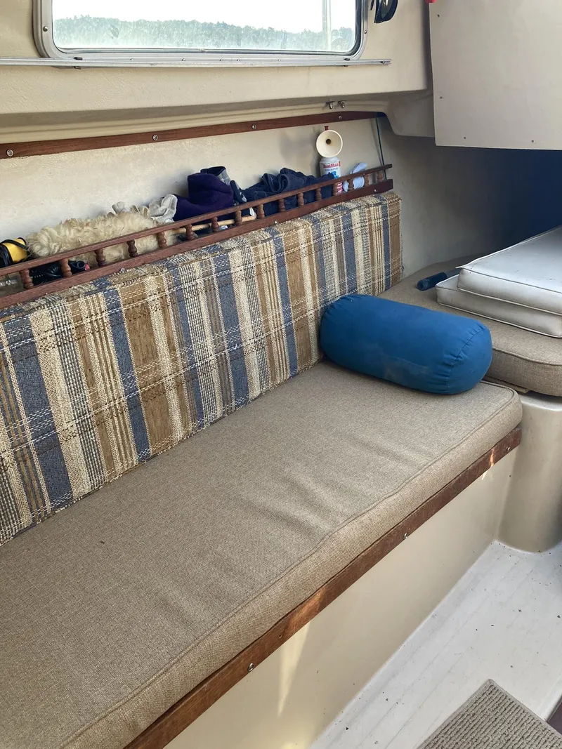 Slide: The Image of Interior of a 1980 Catalina Cat 27 sailboat with plaid seating and a blue pillow. - 3