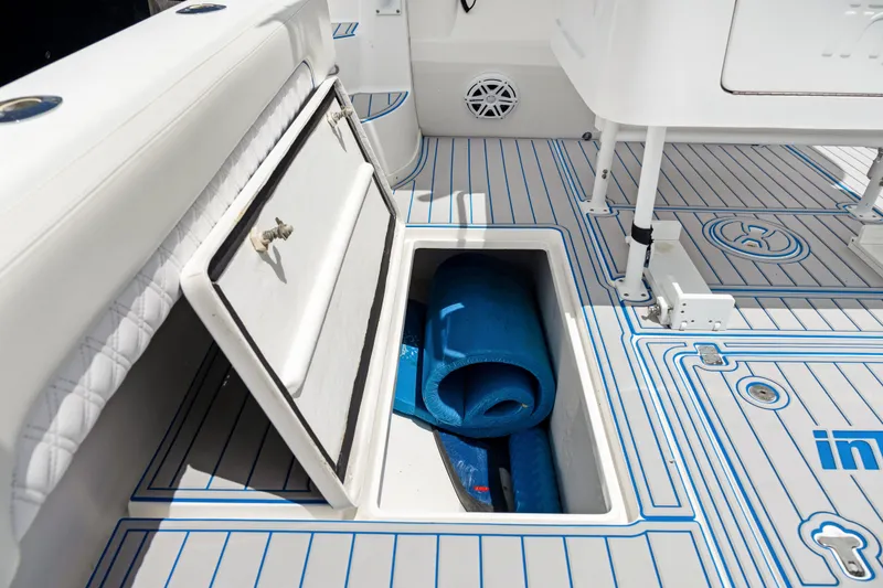 Slide: The Image of 2004 Intrepid 377 Walkaround boat deck with storage compartment and blue mat. - 13